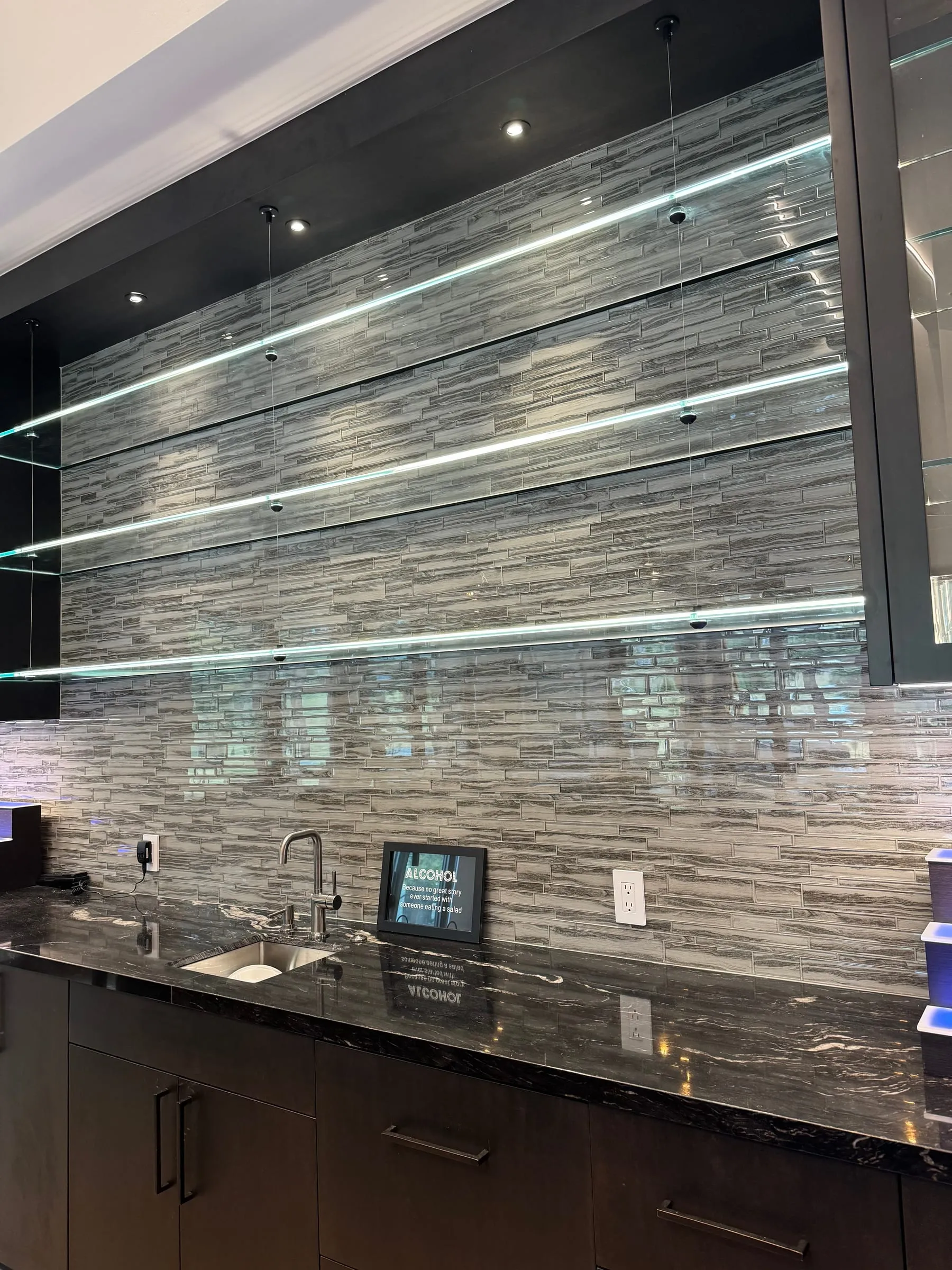 Backlit glass shelves on a home bar wall