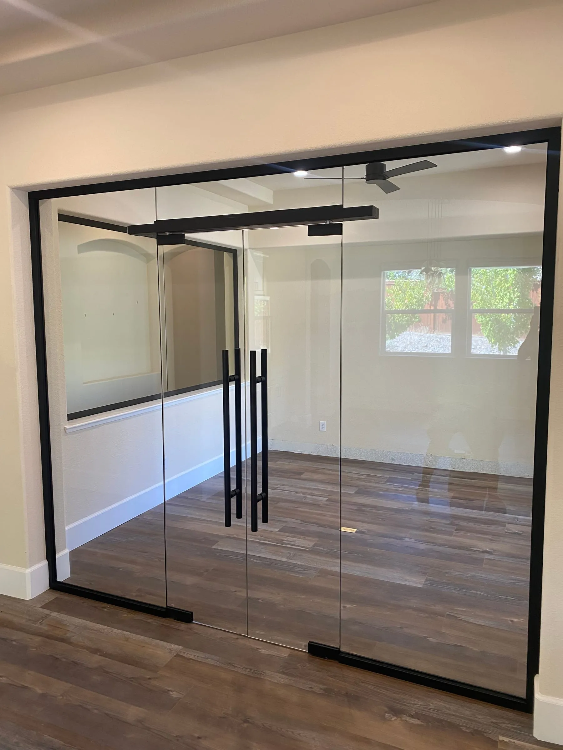 Black-frame glass double doors and wall enclosing a home office