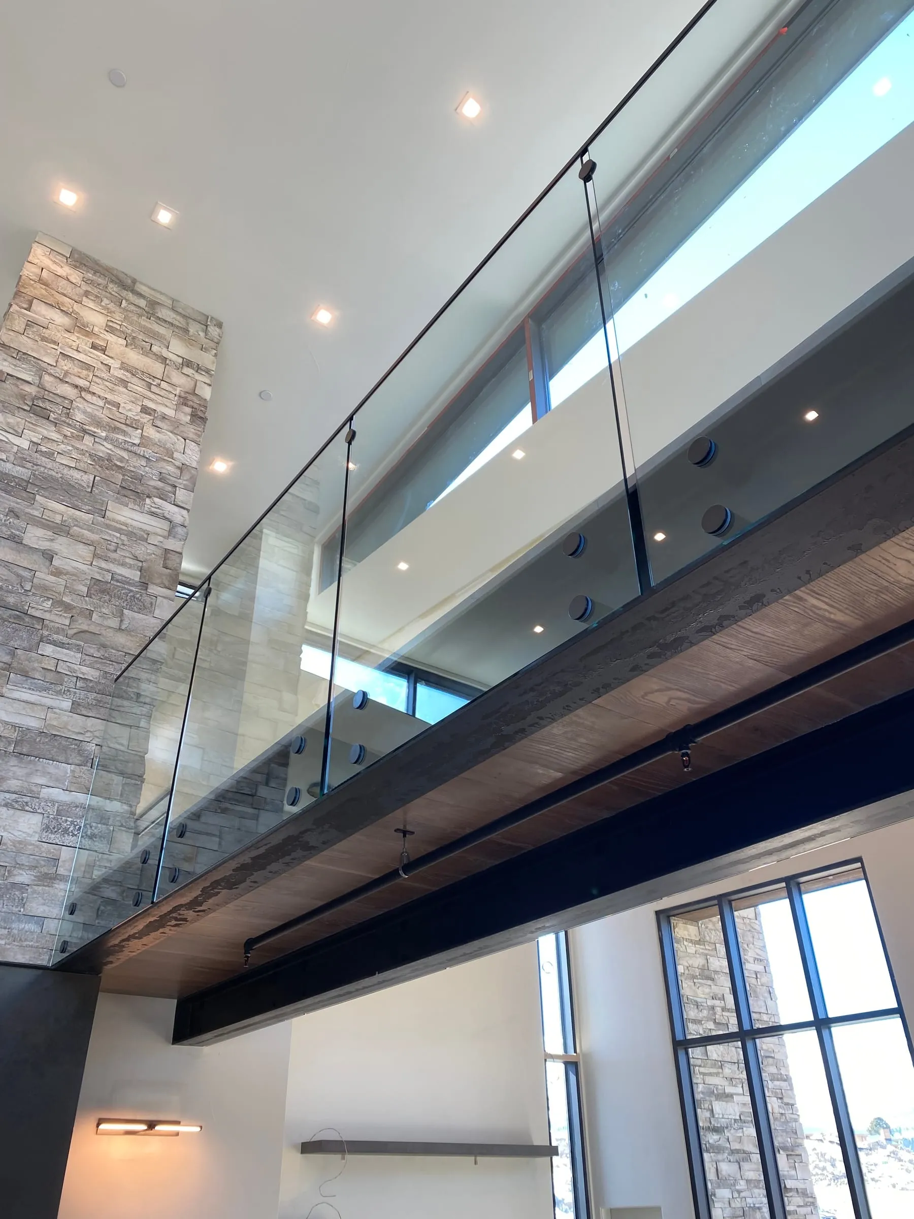 Glass loft balustrade beside a stone wall