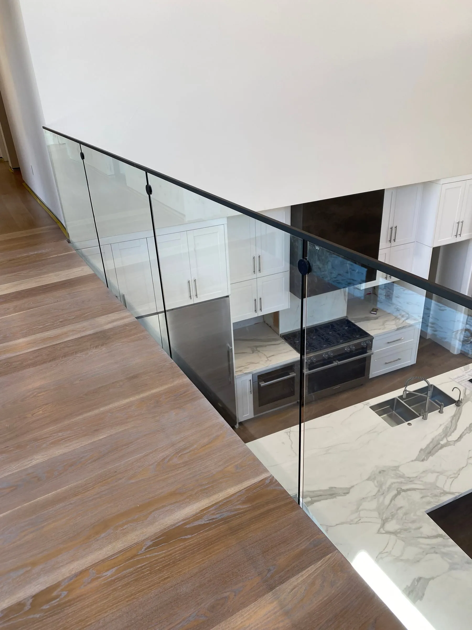 Glass loft railing looking down into a kitchen