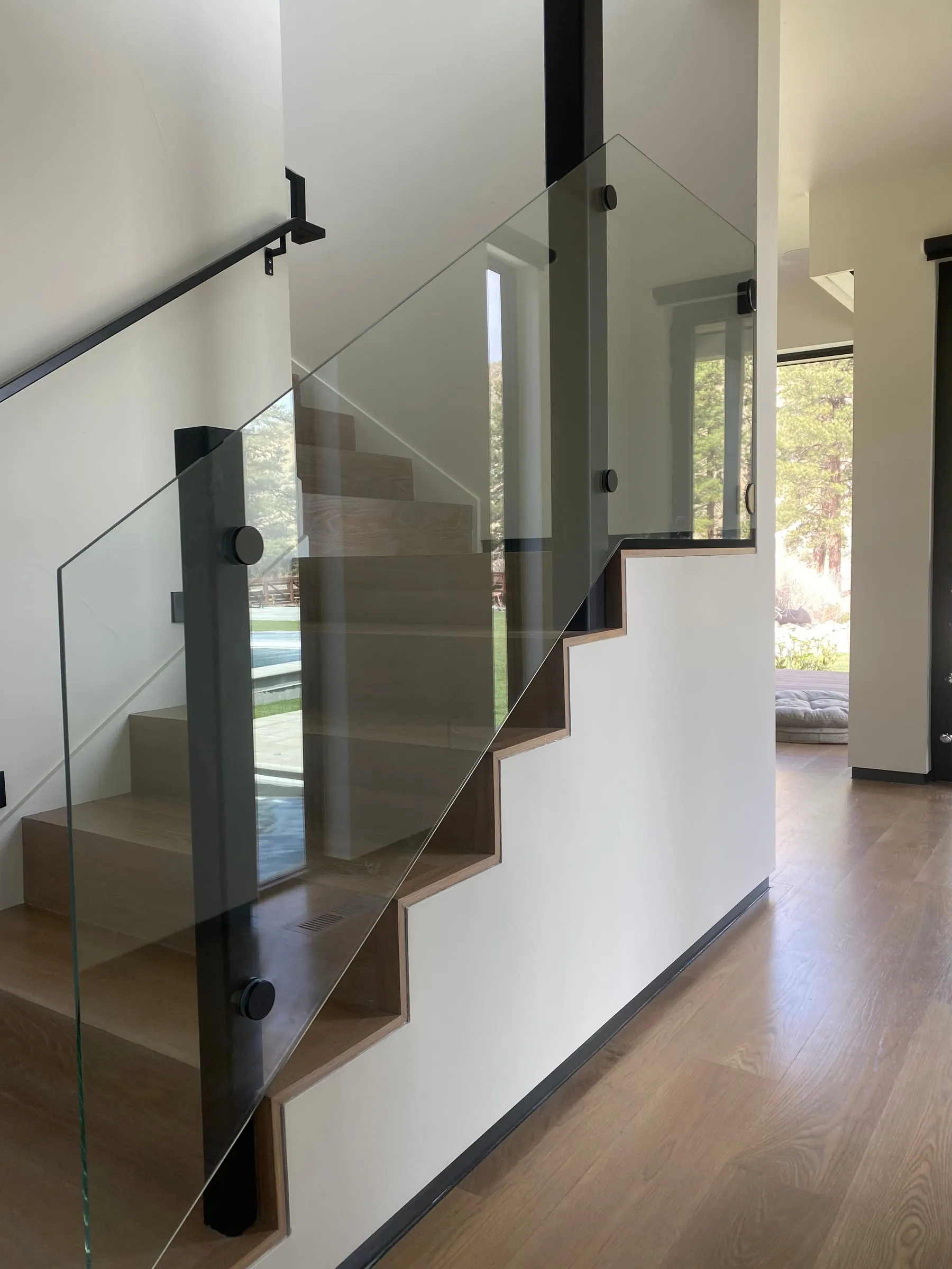 Glass stair panel with a black wall-mounted handrail