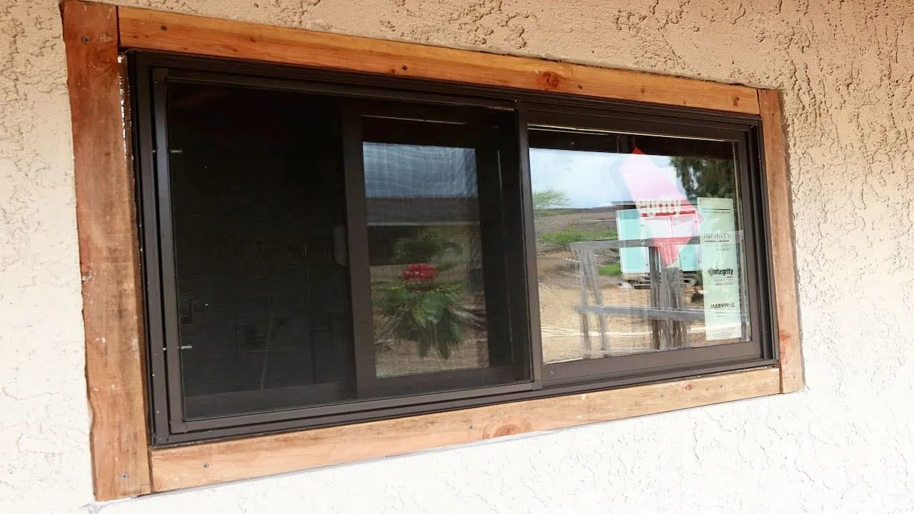 Newly installed dark-frame window on a stucco home
